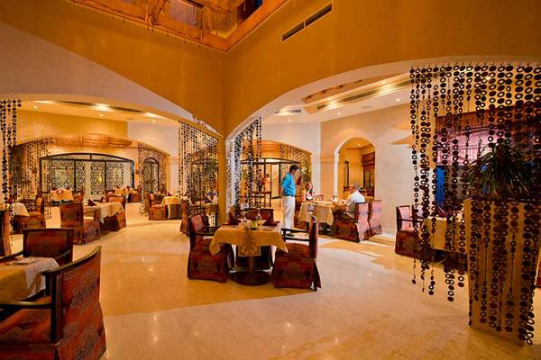 Innenbereich des Amphoras Beach Hotel Restaurants mit runden Tischen, Stühlen und Dekor.