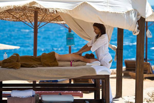 Massage am Strand des Amphoras Beach Hotels unter einem Sonnenschirm.