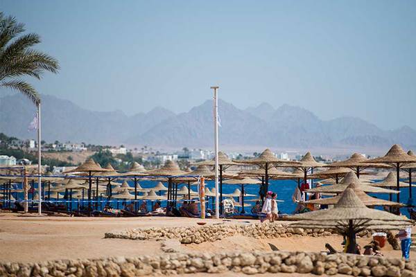 Strand des Amphoras Beach Hotels mit vielen Sonnenschirmen und Bergen im Hintergrund
