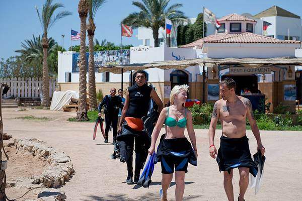 Divers am Amphoras Beach Hotel, einige mit Tauchausrüstung, gehen zum Strand.