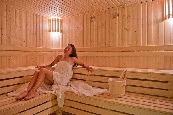 Eine Frau sitzt in einer Sauna des Amphoras Beach Hotels und hält einen Handtuch.