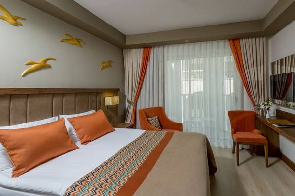 Innenansicht eines Hotelzimmers mit zwei Betten, Sesseln, Schreibtisch und Fernseher.