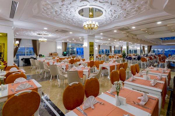 Restaurant des Side Royal Palace Hotels mit vielen Tischen und Stühlen, die für Gäste bereit sind.