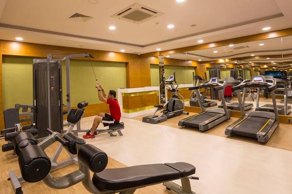Fitnesscenter im Side Royal Palace Hotel mit verschiedenen Geräten und einem Mann, der an einem Zugkraftgerät arbeitet.