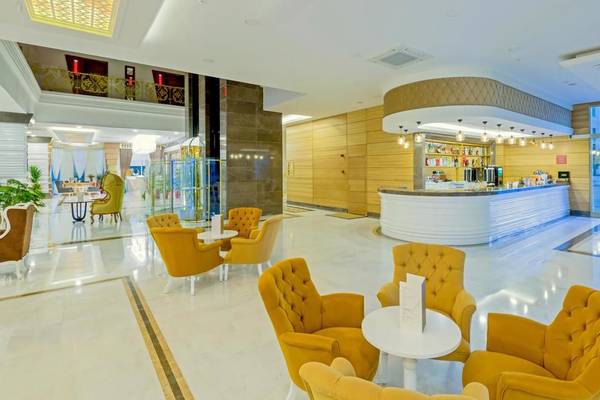 Innenansicht der Lobby des Side Royal Palace Hotel & Spa mit gelben Sesseln und einer Theke