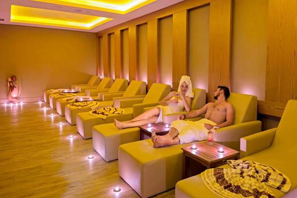 Paar im Side Royal Palace Hotel & Spa in der Lounge-Ecke, beide mit Handtüchern auf den Köpfen, umgeben von gelben Sesseln.