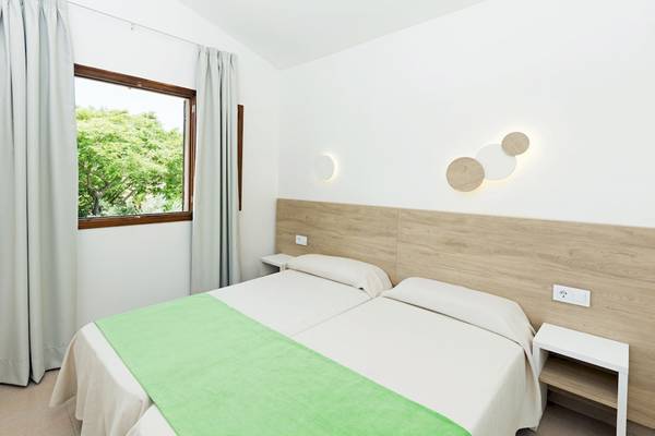 Doppelbett-Zimmer im HSM Club Torre Blanca mit grüner Decke, weißen Kissen und weißem Kopfteil.