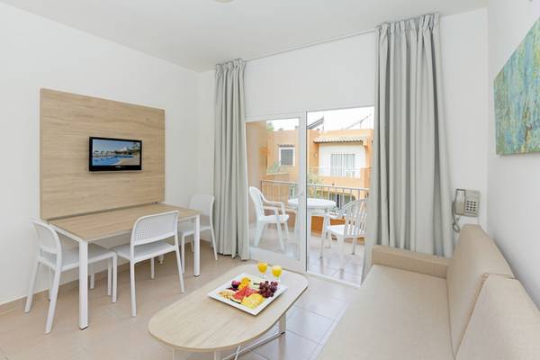 Wohnbereich des HSM Club Torre Blanca mit Tisch, Stühlen, Fernseher und Balkon.