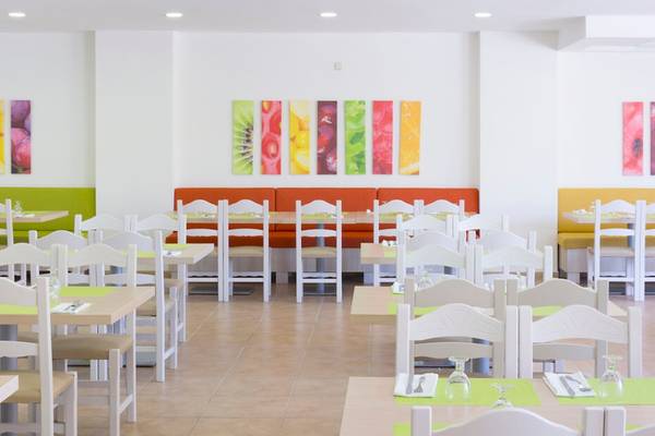 Innenansicht des Restaurants im HSM Club Torre Blanca mit farbenfrohen Wandgemälden und gedeckten Tischen.