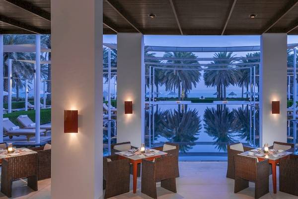 Innenansicht des Restaurants im The Chedi Muscat mit Blick auf den Pool und die Terrasse.