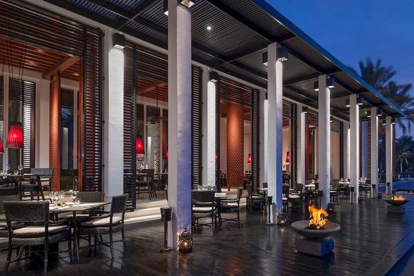 Abendessen im Chedi Muscat Hotel mit Außensitzbereich, Feuerstellen und Blick auf den Strand.