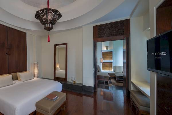 Luxuriöses Schlafzimmer im The Chedi Muscat mit einem großen Bett, Holzmöbeln und einer modernen Einrichtung.