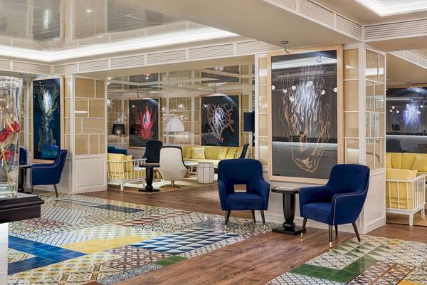 Lobby des H10 Las Palmeras Hotels mit blauen Stühlen und bunten Fliesen.
