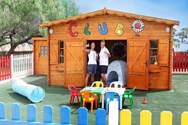 Zwei Frauen vor einem Clubhaus von H10 Las Palmeras mit bunten Spielsachen und Tischen.