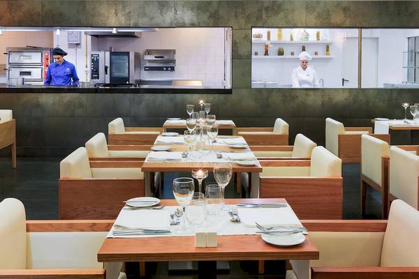 Innenansicht des Restaurants im H10 Las Palmeras Hotel mit gedeckten Tischen und Köchen, die im Hintergrund arbeiten.
