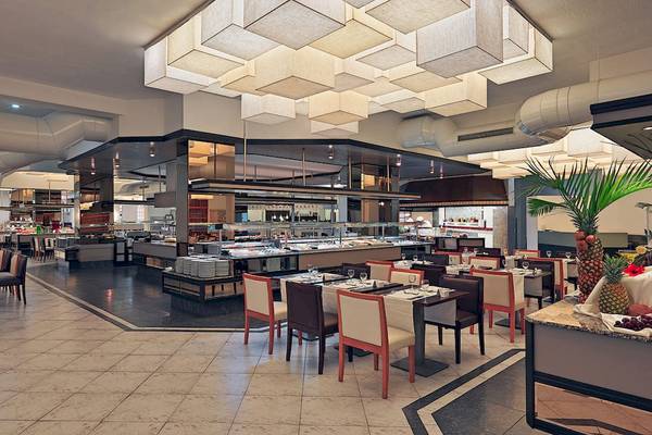 Innenansicht des Restaurants des H10 Las Palmeras Hotels mit geometrischen Deckenleuchten, Buffet und gedeckten Tischen.