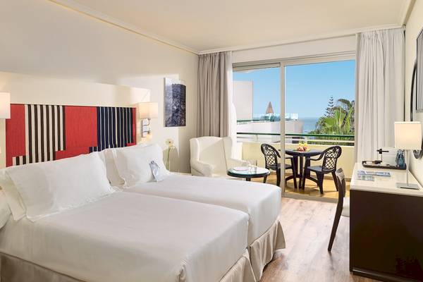 Doppelzimmer im Hotel H10 Las Palmeras mit zwei Betten, einem Balkon und Meerblick.