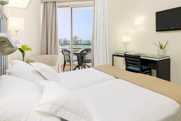 Ein modernes Hotelzimmer mit Blick auf das Meer, mit einem Bett, Schreibtisch, Balkon und Fernseher.