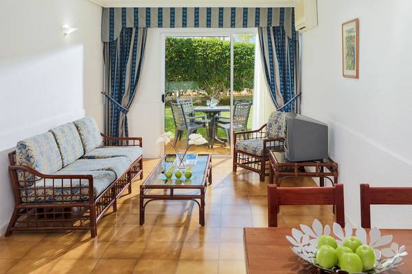 Wohnbereich im H10 Las Palmeras Hotel mit Blick auf den Garten und Möbeln.