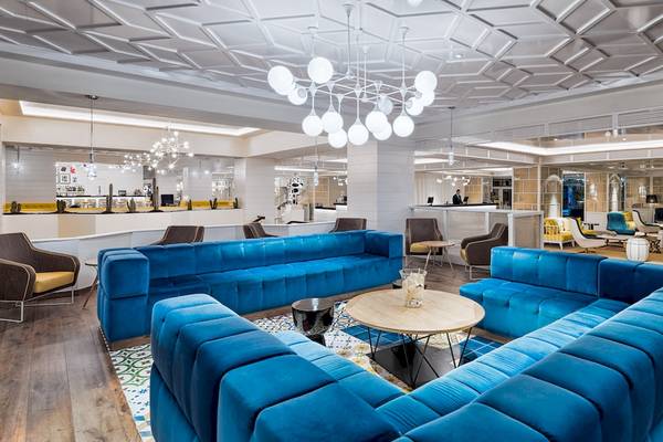 Lobby des H10 Las Palmeras Hotels mit blauen Sofas, Kronleuchter und modernem Design.