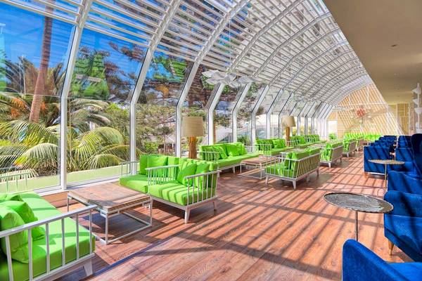 Loungebereich des H10 Las Palmeras Hotels mit grünen Sofas und blauen Sesseln.