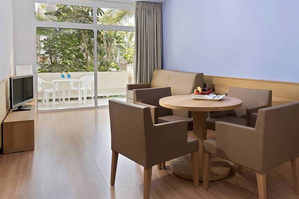 Wohnbereich des Tabaiba Princess Hotels mit Tisch, Stühlen und Fernseher.