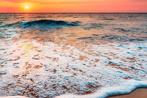 Sonnenuntergang am Meer mit sanften Wellen und einem Hotel namens Tabaiba Princess.