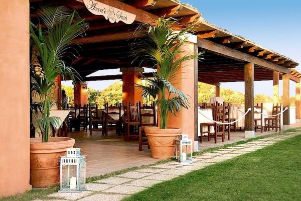 Außenbereich des Alma Resorts mit einem Pavillon, gedeckten Tischen und großen Topfpflanzen.