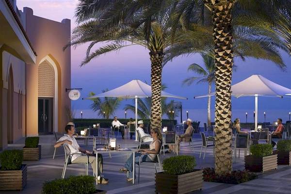 Terrasse des Shangri-La Barr Al Jissah Resort & Spa mit Gästen und Palmen bei Nacht