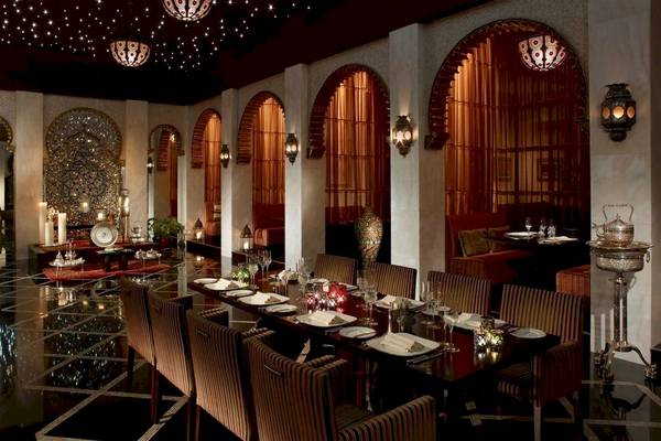 Innenbereich des Shangri-La Barr Al Jissah Resorts & Spa mit gepolsterten Stühlen und einem langen Esstisch.