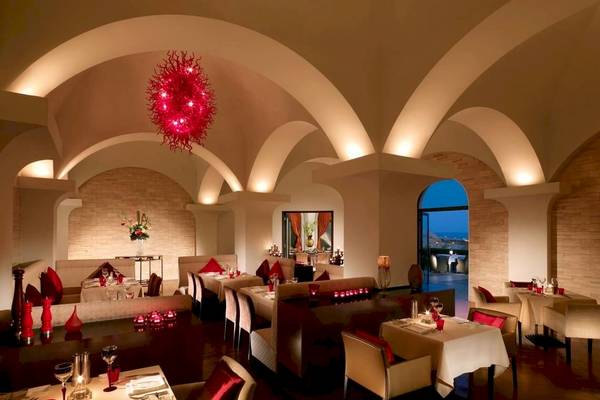 Innenansicht des Restaurants Shangri-La Barr Al Jissah Resort & Spa - Al Bandar mit roten Leuchten und eleganten Tischdekorationen.