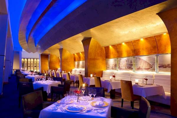 Innenansicht des Restaurants Shangri-La Barr Al Jissah Resort & Spa - Al Bandar mit blauer Beleuchtung und eingerichteten Tischen.