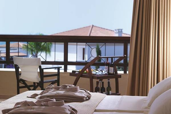 Zimmer im Mitsis Royal Mare Thalasso & Spa Resort mit Balkon, Bett, Kleidern und Aussicht