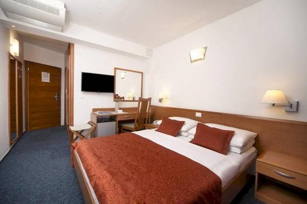 Ein ruhiges und modernes Zimmer im BlueSun Hotel Berulia mit einem Bett, Schreibtisch und Fernseher.