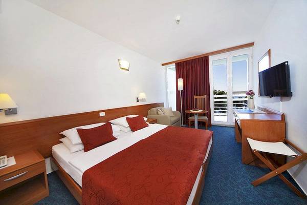 Interieur eines Zimmers im BlueSun Hotel Berulia mit Doppelbett, Nachttischen, Fernseher und Schreibtisch.