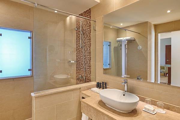 Badezimmer im Steigenberger Aqua Magic Hotel mit großer Glasdusche, Waschbecken und Spiegel.