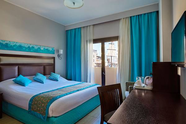 Hotelzimmer im Steigenberger Aqua Magic mit blauen Vorhängen, Doppelbett und Schreibtisch.
