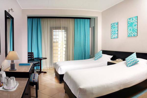 Doppelzimmer im Steigenberger Aqua Magic Hotel mit zwei Betten, Fernseher, Schreibtisch und Dekoration.