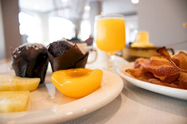 Frühstücksbuffet im Calypso Hotel mit Muffins, Pfirsich, Orangensaft und Speck.
