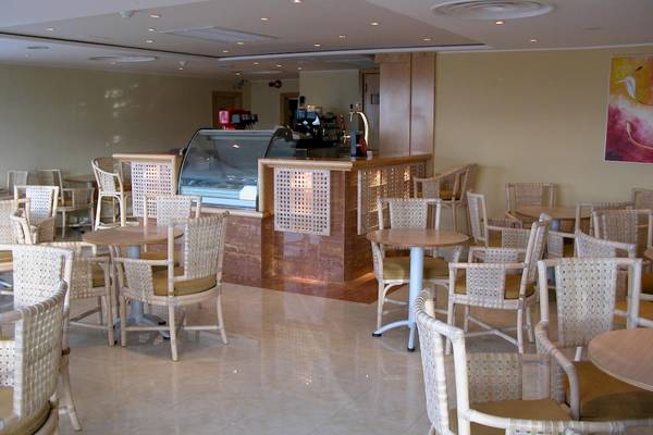 Innenbereich des Calypso Hotels mit Café, Tischen und Stühlen.