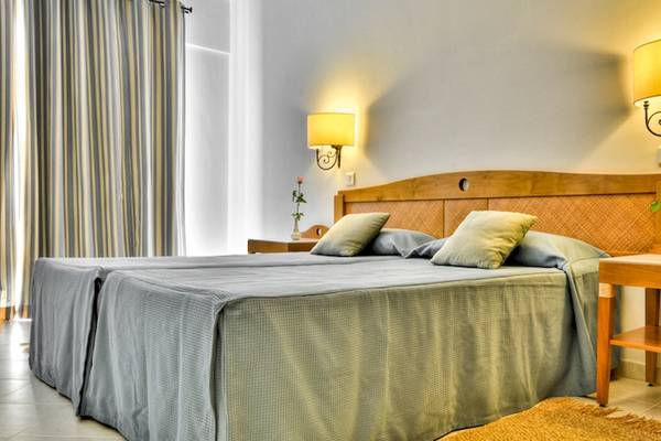 Doppelbettzimmer im Calypso Hotel mit zwei Betten, Nachttischen und Lampen an der Wand.