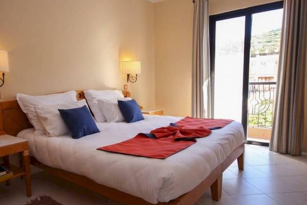 Schlafzimmer im Calypso Hotel mit einem Bett, Kissen und Decken, neben einem Fenster.