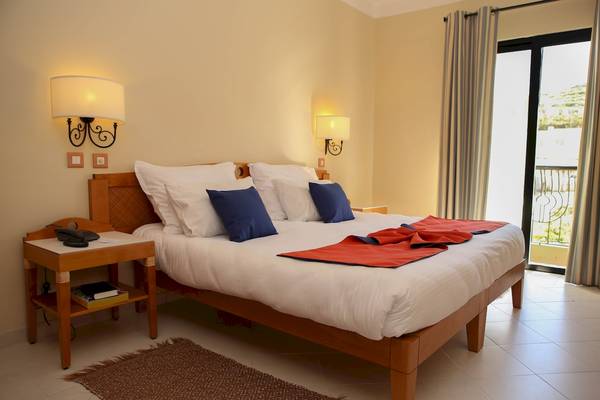 Ein Doppelbett mit weißen Laken und Kissen im Zimmer des Calypso Hotels.