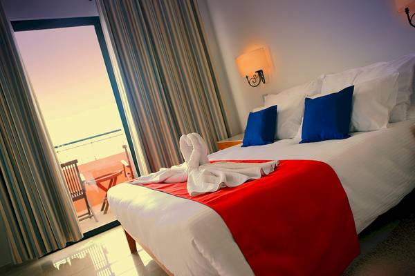 Ein luxuriöses Hotelzimmer mit einem Bett, das auf das Balkonfenster ausgerichtet ist.