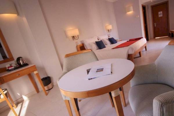 Innenansicht eines Zimmers im Calypso Hotel mit einem Bett, Tisch, Stühlen und Dekoration.