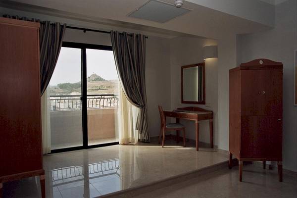 Zimmer im Calypso Hotel mit Balkon, Schreibtisch und Spiegel.