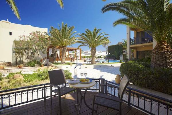 Balkon des Atlantis Beach Hotel in Kreta mit Tisch, Cocktails und Ausblick auf den Pool.