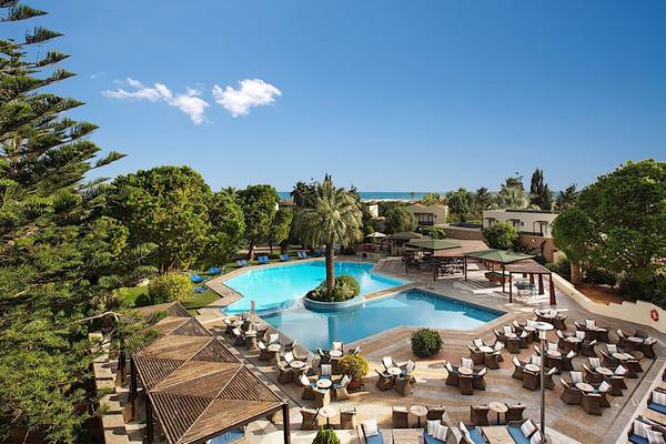 Luftaufnahme des Cretan Malia Park Hotels mit Pool und umliegenden Bäumen und Gebäuden.