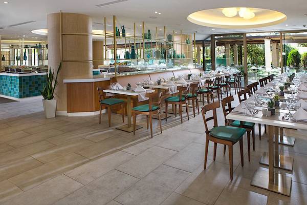 Innenansicht des Restaurants im Cretan Malia Park Hotel mit gedeckten Tischen und Stühlen.