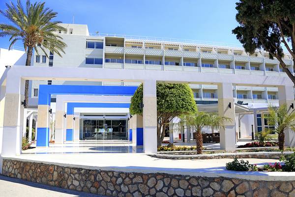 Vorderansicht des Blue Bay Beach Resorts mit Eingang, Säulen und Palmen